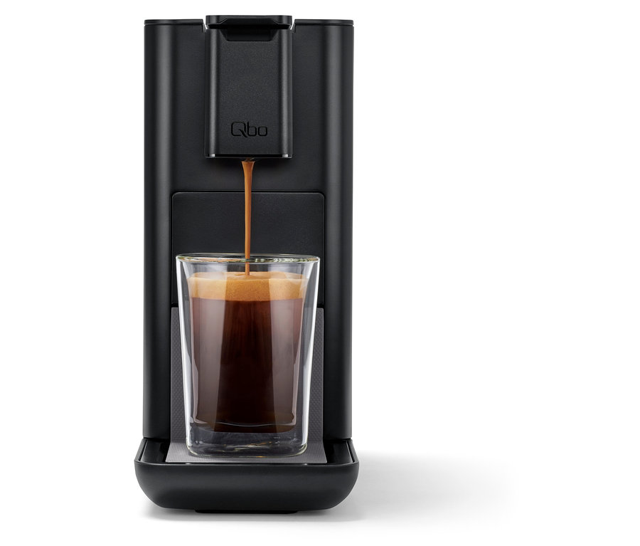 Le café coule d'une machine à café Qbo ICONIC Dark Chrome dans un verre.