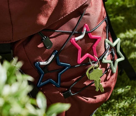Trois mousquetons «
toile
» de différentes couleurs sont fixés sur un sac à dos.