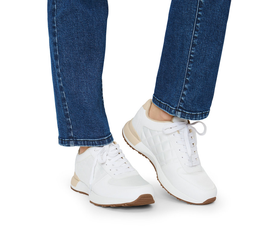 Jambes en jean et baskets blanches.