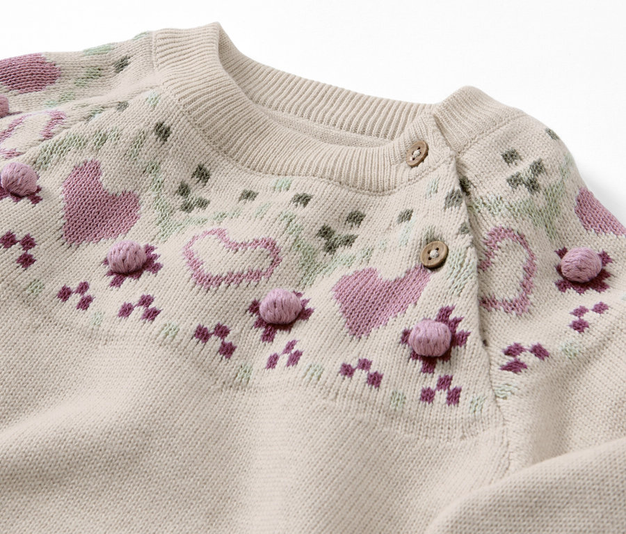 Gros plan sur un pull en maille pour enfant avec un motif norvégien.