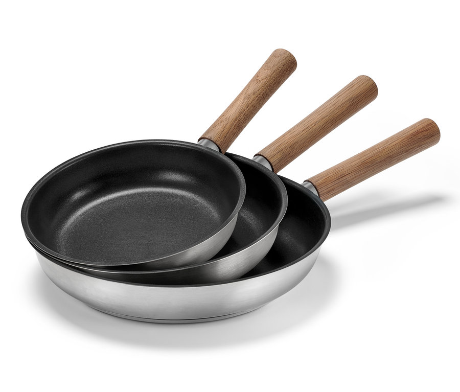 Trois poêles en inox avec manches en bois (20, 24 et 28 cm de diamètre) sont empilées les unes sur les autres.