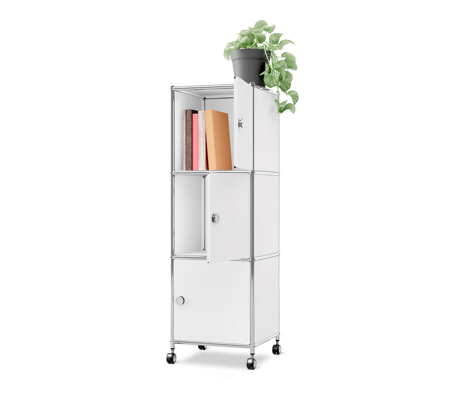 Caisson en métal à roulettes « CN3 » blanc avec trois portes. Trois livres sont rangés dans le compartiment supérieur ouvert. Une porte supérieure et une porte centrale sont légèrement ouvertes, la porte inférieure est fermée. Une plante verte en pot est posée sur le dessus du caisson.