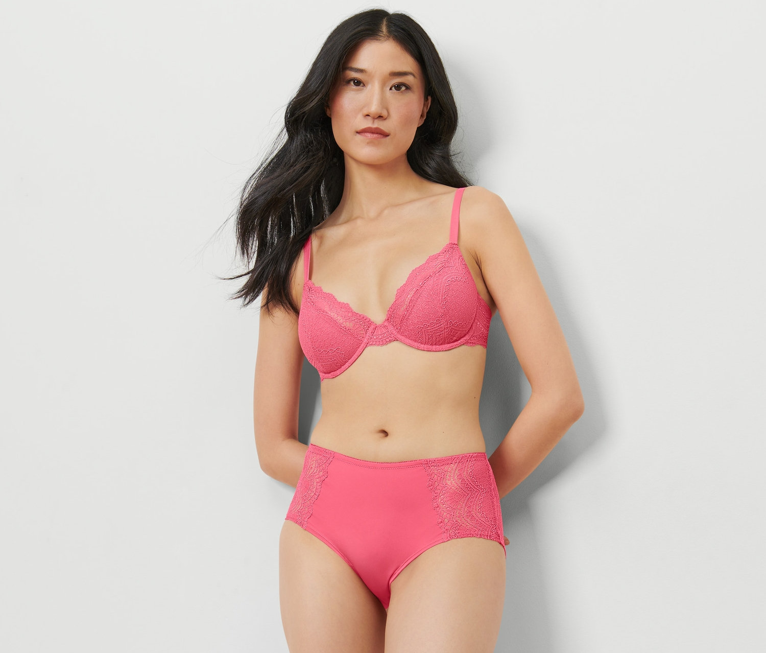 Une femme pose en studio en portant un soutien-gorge rose et une culotte mi-haute.