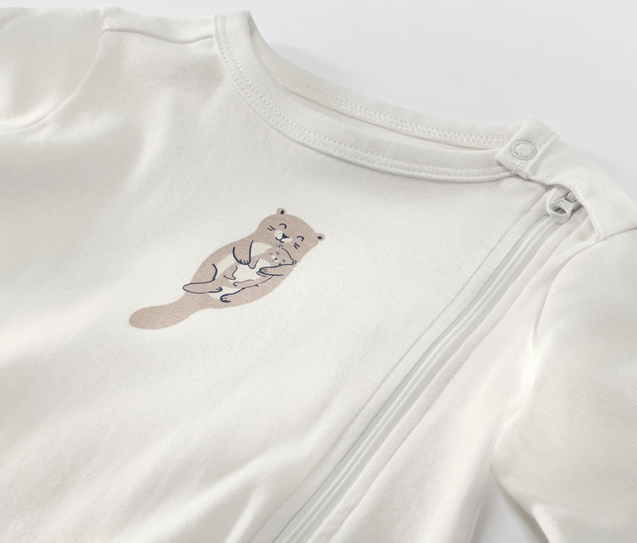 Gros plan sur un pyjama blanc pour bébé avec un motif de loutre.