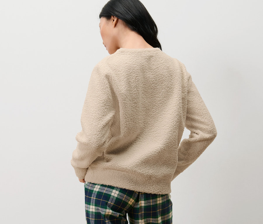 Femme vue de dos portant un sweatshirt moelleux et un pantalon à carreaux.