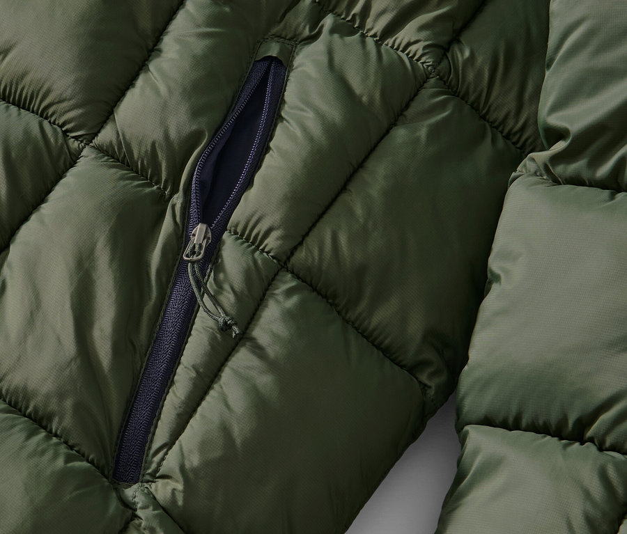 Détail d'une veste matelassée kaki avec une fermeture éclair partiellement ouverte.