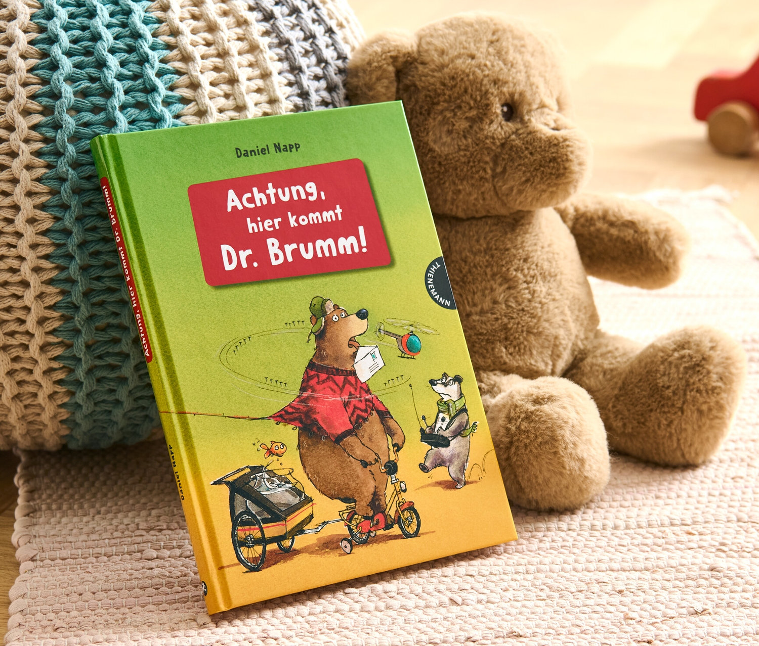 Livre « Achtung, hier kommt Dr. Brumm ! » à côté d'un ours en peluche et d'une voiture en bois.