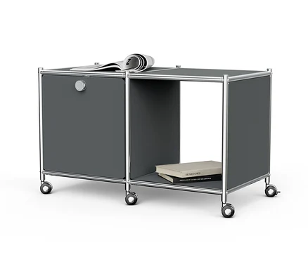Table d’appoint métallique grise « CN3 » avec 1 abattant, roulettes, un journal sur le dessus et des livres dans le compartiment ouvert.