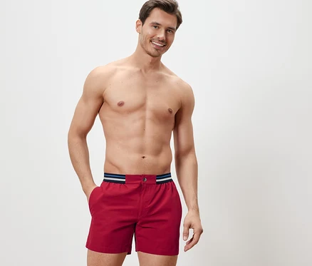 Homme posant en short de bain rouge.