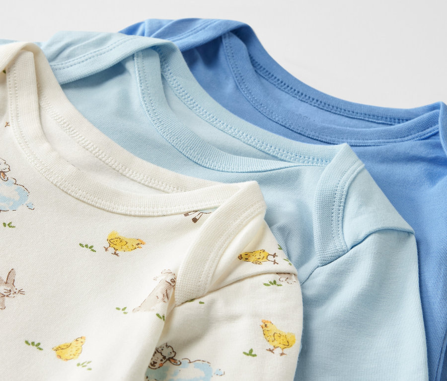 Gros plan sur trois bodys bleus pour bébé avec fonction évolutive.