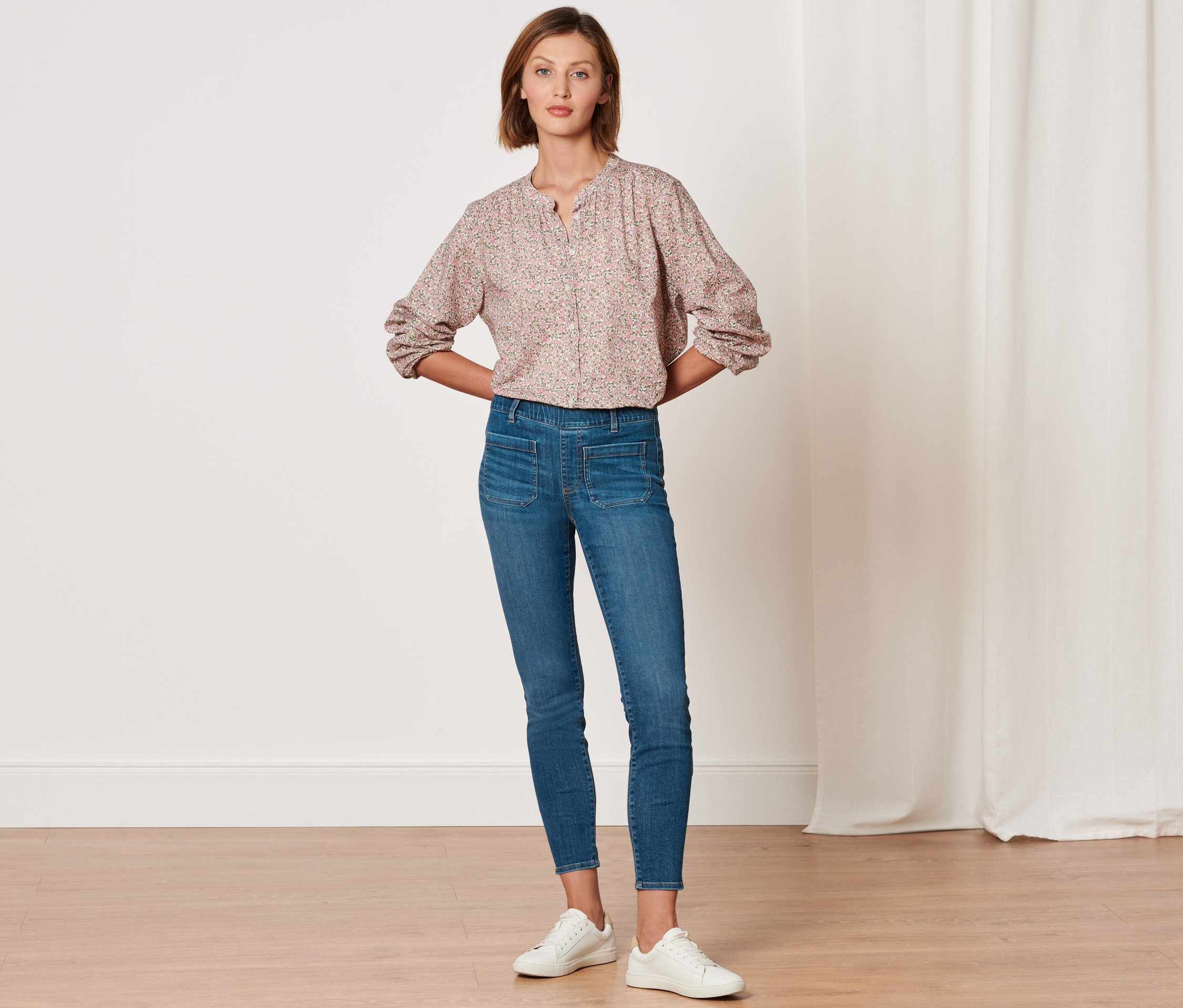 Une femme pose en tregging « Fit Nelly » et un chemisier à motifs.