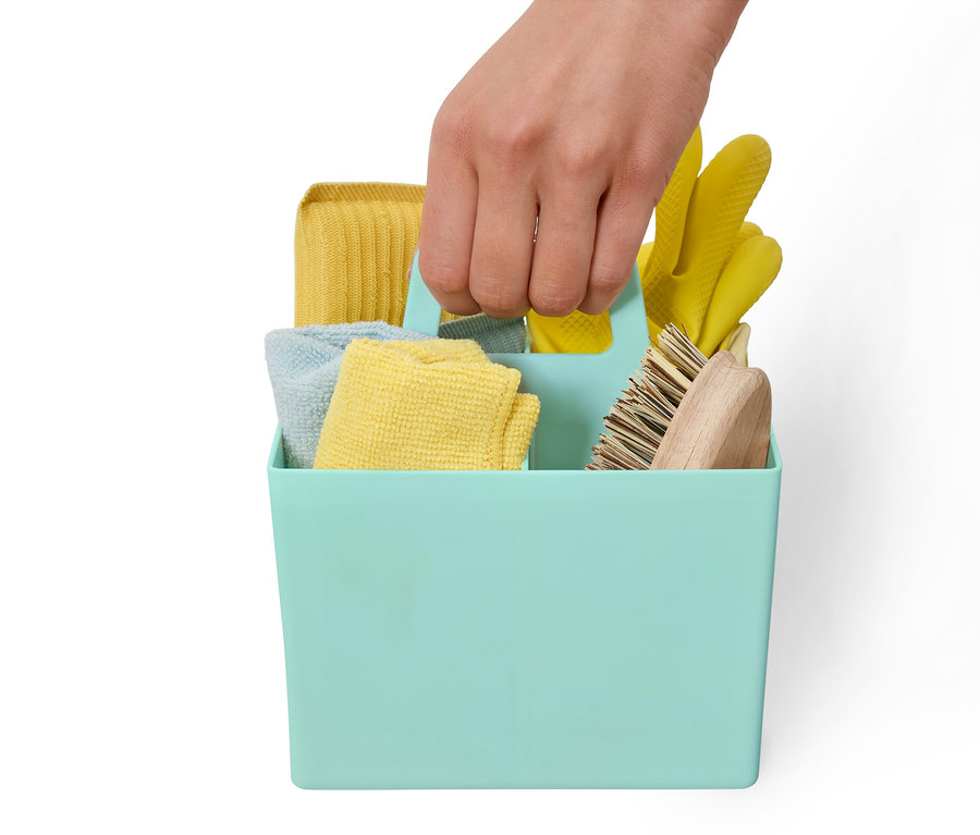 Une main tient un panier de rangement bleu-vert contenant des produits de nettoyage.