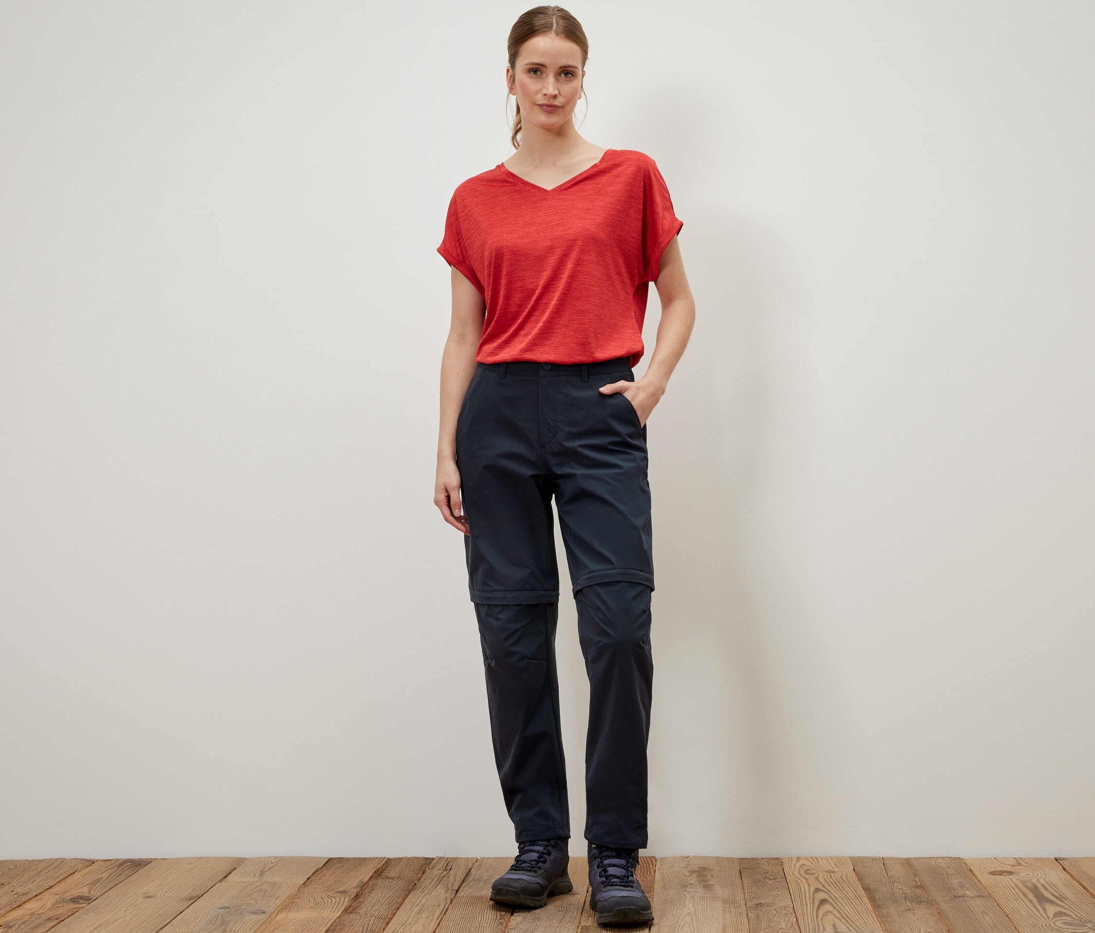 Femme debout portant un t-shirt rouge et un pantalon fonctionnel 2 en 1 bleu.