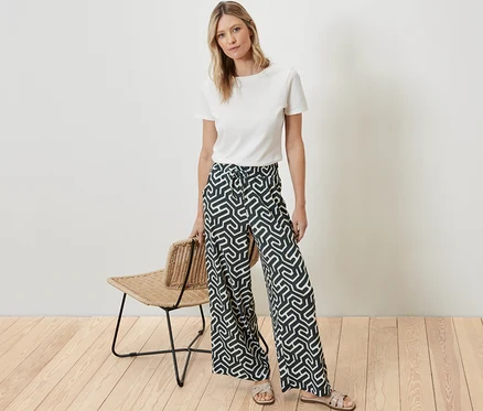 Une femme debout porte un t-shirt blanc et un pantalon imprimé à enfiler avec effet Crinkle.