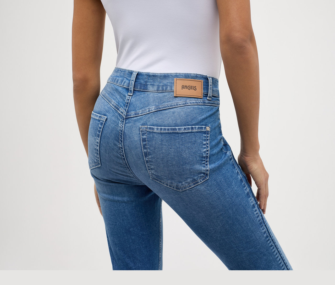 Vue de dos d'une personne portant un jean Angels « Ornella Seam » Slim Fit 7/8 bleu clair et un haut blanc.