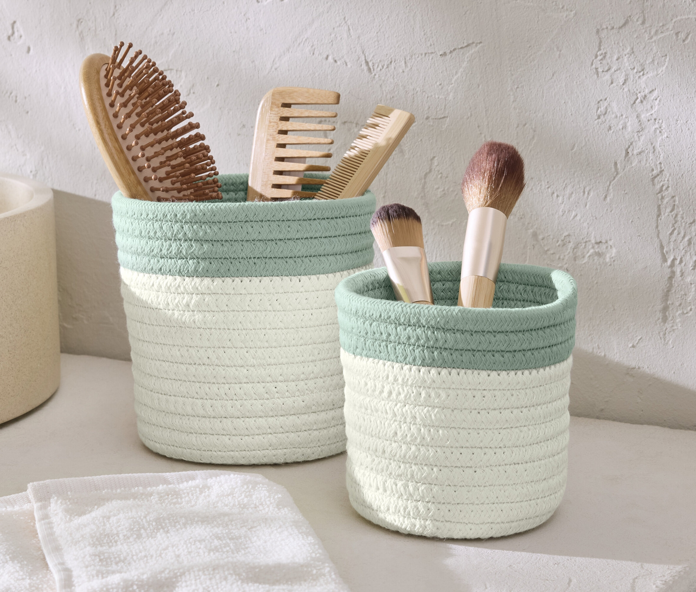 Deux paniers de rangement avec des brosses et des pinceaux de maquillage.