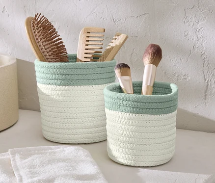 Deux paniers de rangement avec des brosses et des pinceaux de maquillage.