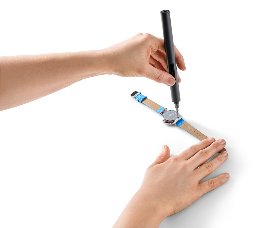 Des mains utilisent un mini-tournevis sans fil pour réparer une montre.