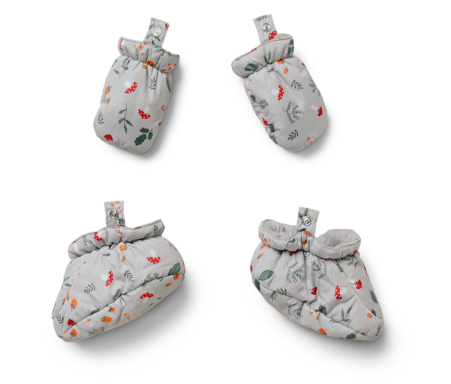 Quatre chaussons pour bébé avec des motifs de champignons, de feuilles et de glands sur fond blanc.