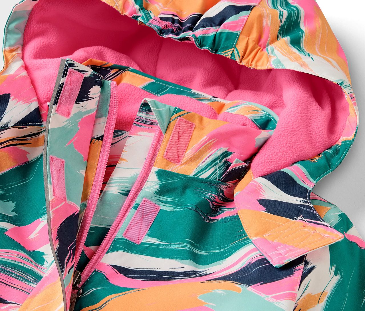 Détail d'une veste à capuche avec un motif coloré et une doublure rose.