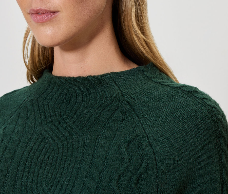 Gros plan d'une femme portant un pull en tricot vert.