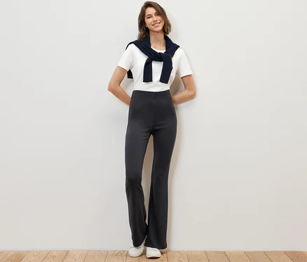 Une femme pose debout en portant un legging évasé.