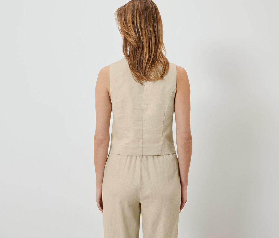 Vue de dos d'une femme portant un gilet en lin et un pantalon.