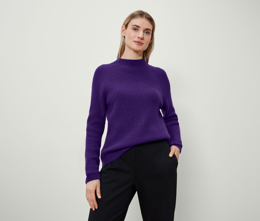 Femme posant en pull violet et pantalon noir.