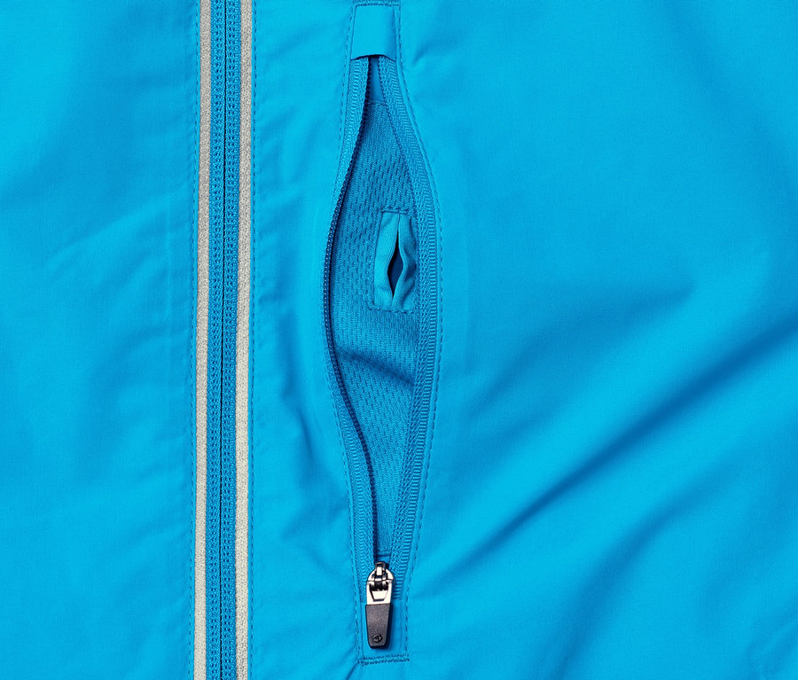 Détail d'une veste fonctionnelle coupe-vent bleue avec une poche zippée partiellement ouverte.