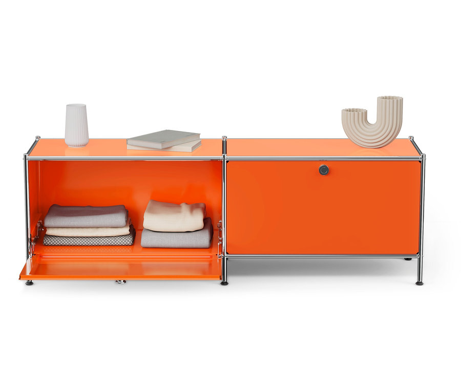 Meuble bas orange avec une porte ouverte révélant des vêtements pliés, à côté d'un vase et de livres.