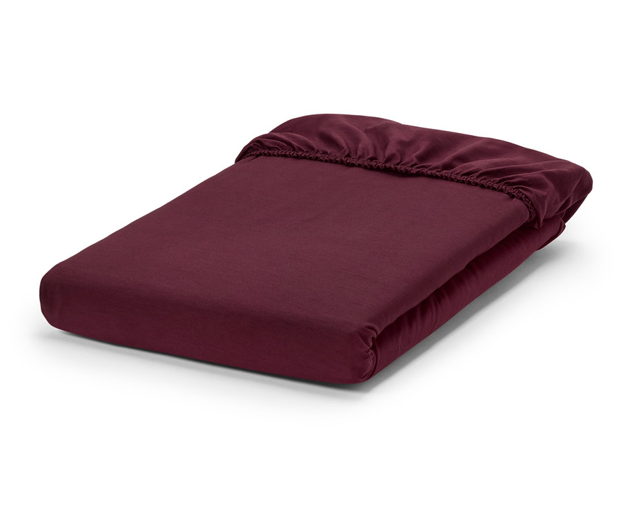 Un drap-housse bordeaux plié sur un fond blanc.