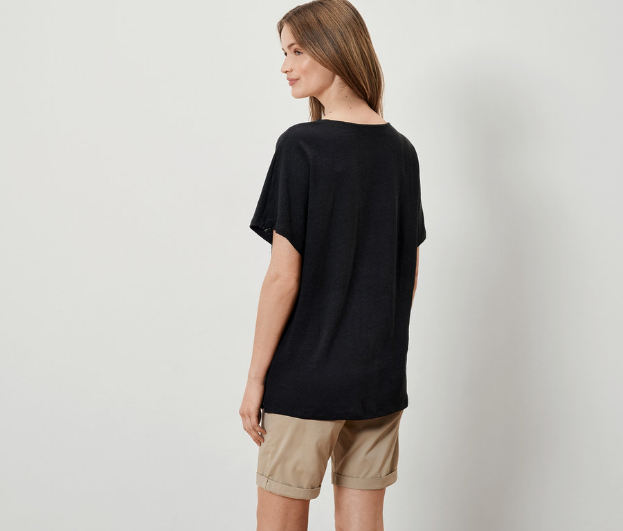 Femme posant en t-shirt noir en lin mélangé et short beige.