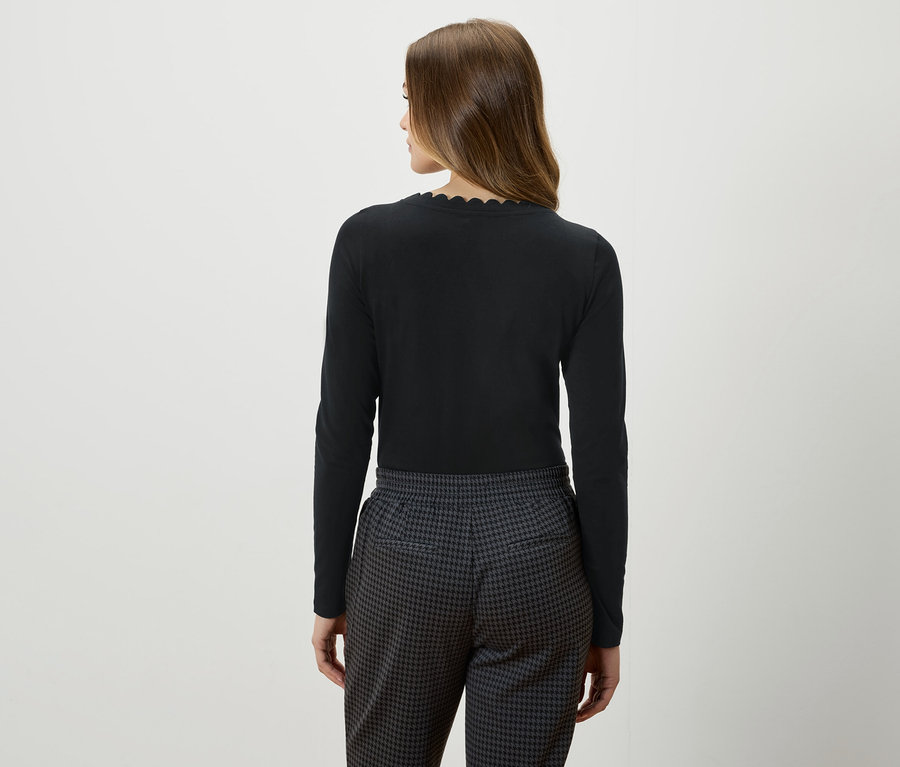 Vue arrière d'une femme aux cheveux bruns portant un haut noir à manches longues et un pantalon gris et noir.