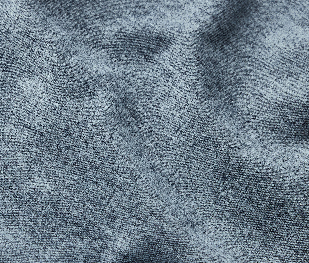 Gros plan sur une texture de tissu gris avec un motif délicat et des plis.
