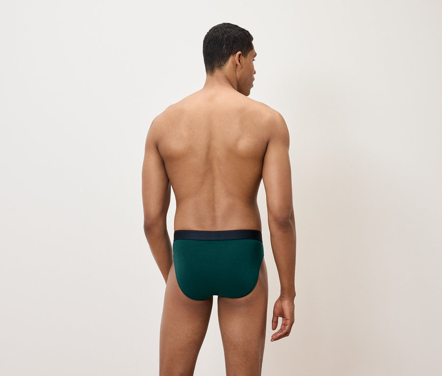 Un homme, dos à la caméra, porte un slip vert.