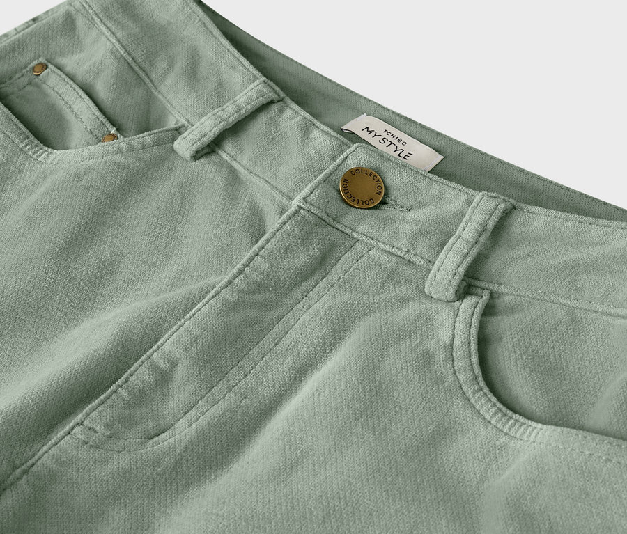 Gros plan d'un pantalon en velours côtelé vert clair avec bouton et passants de ceinture.