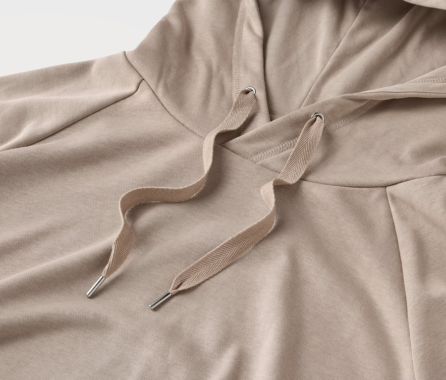 Gros plan sur un sweat à capuche beige avec cordon de serrage.