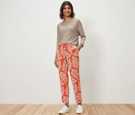 Femme debout portant un haut beige et un pantalon en jersey imprimé.