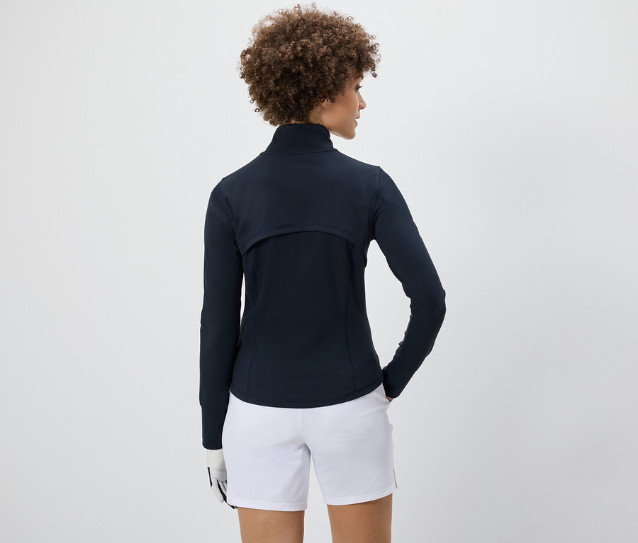 Femme portant une veste fonctionnelle et un short blanc.