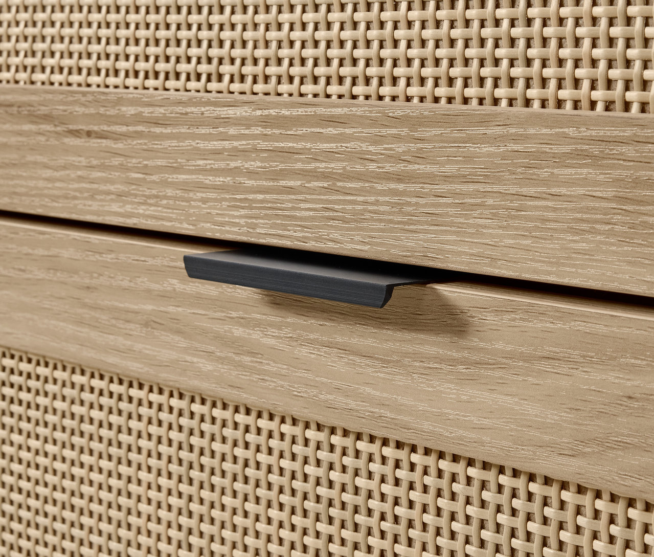 Détail d'une commode avec tiroir en bois et façade en osier.