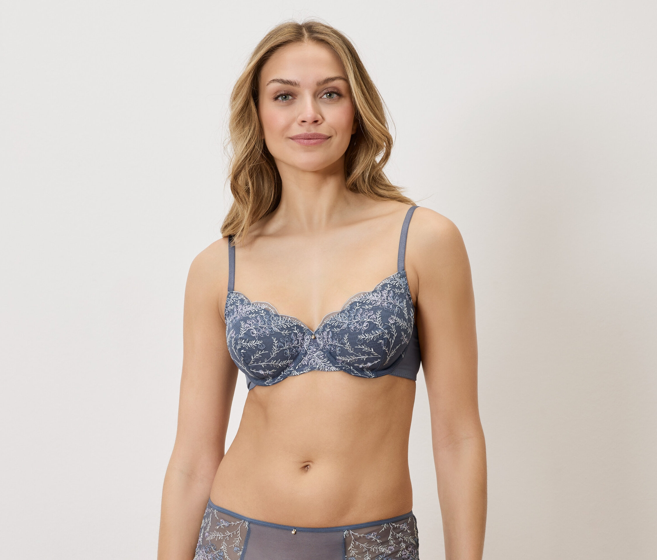 Une femme porte un soutien-gorge bleu à motifs floraux et des sous-vêtements assortis.