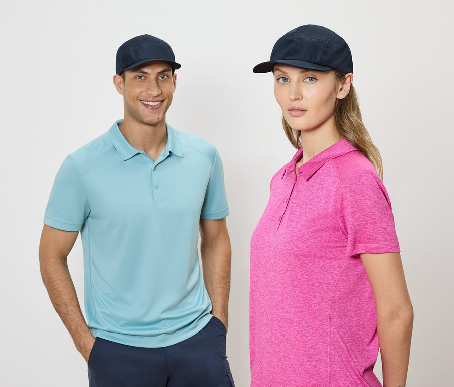 Un homme et une femme se tiennent côte à côte, portant des casquettes bleues et des polos sur un fond neutre.