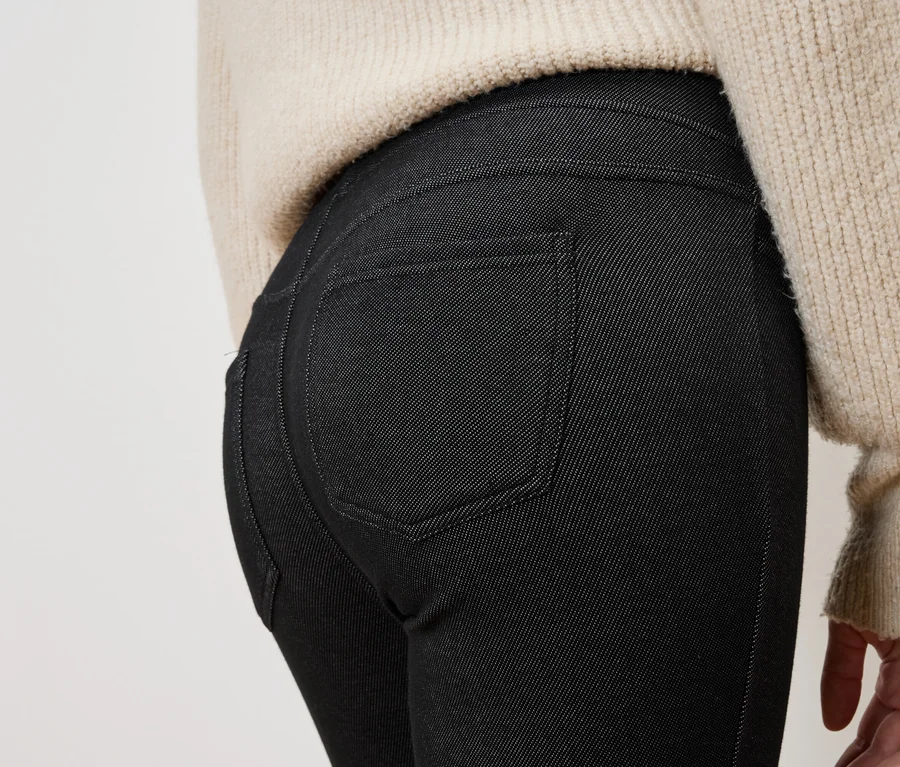 Gros plan sur le dos d'une personne portant un jean noir et un pull beige.