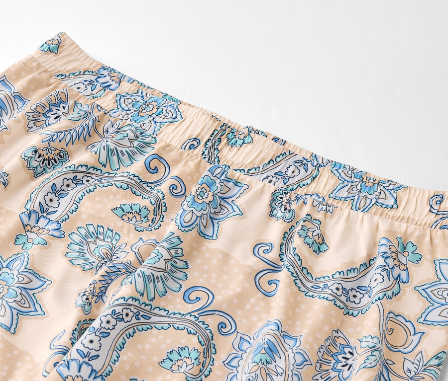 Gros plan d'un pantalon beige clair avec un motif floral bleu et une taille élastique.