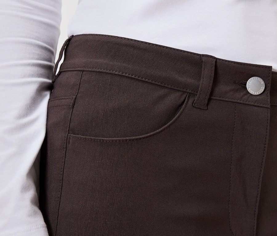 Gros plan d'une femme portant un haut à manches longues et un pantalon marron boutonné.