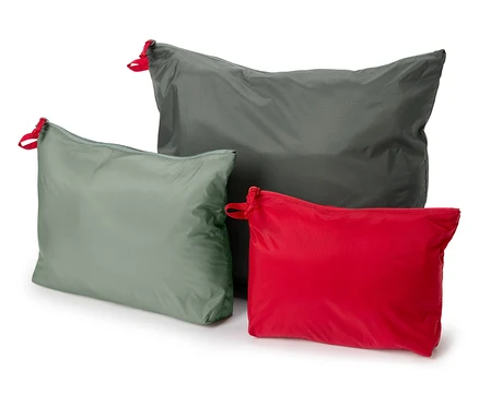 Trois sacs en tissu gris, vert et rouge avec des détails de cordon de serrage rouge reposent sur un fond blanc.
