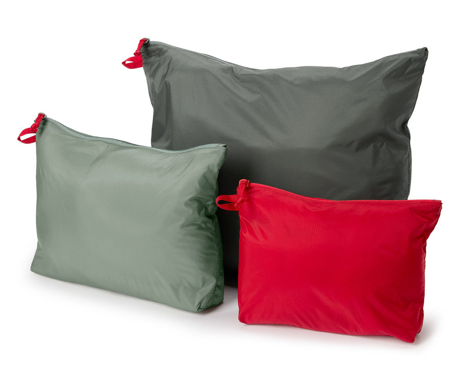 Trois sacs en tissu gris, vert et rouge avec des détails de cordon de serrage rouge reposent sur un fond blanc.