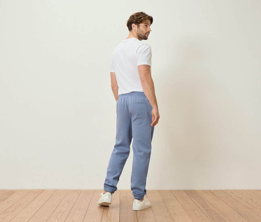 Homme en pantalon de jogging bleu clair et t-shirt blanc, vu de dos.