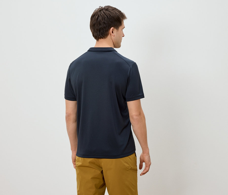 Homme vu de dos portant un polo bleu marine et un pantalon kaki sur fond blanc.
