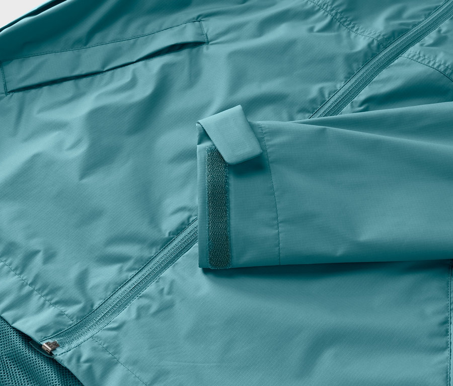 Gros plan d'une veste turquoise avec fermeture éclair et velcro sur la manche.